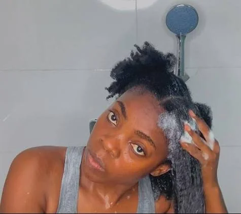 4C hair care routine with coily hair being gently sectioned and detangled in a bright bathroom