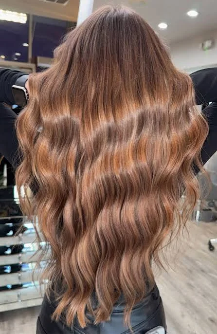 Light brown hair with soft warm waves and subtle highlights creating a natural dimensional finish